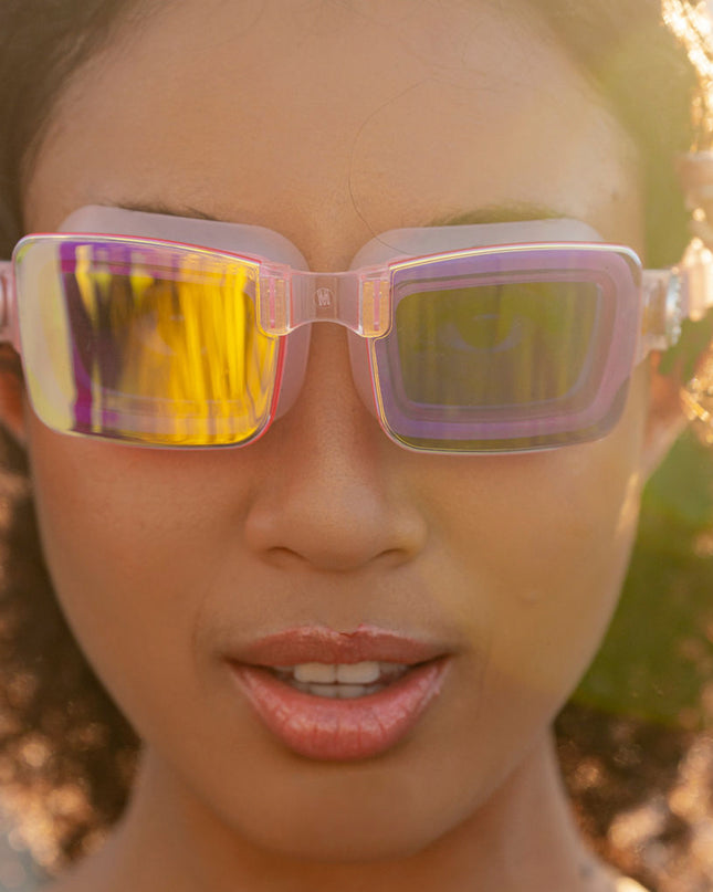 woman wearing vivacity swim goggles in blush pink showing sleek frameless goggles with mirrored lens