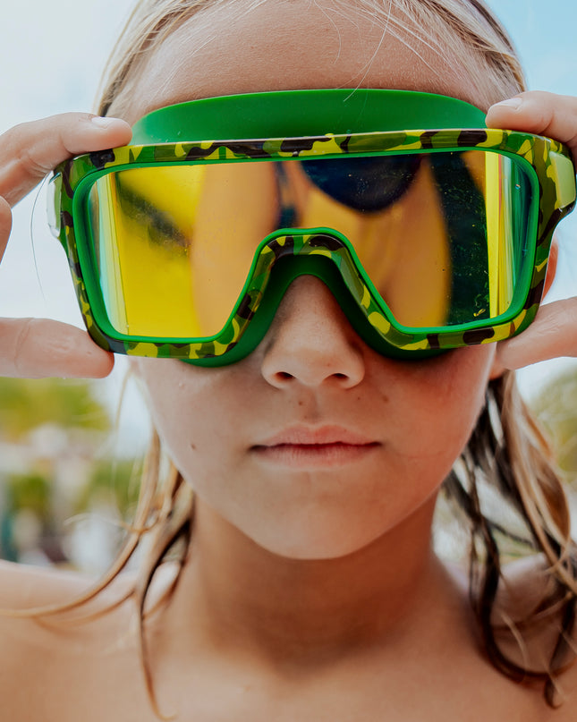boy poolside wearing special ops kids' swim goggles in guerilla green showing wide frame swim goggles and a green camo printed frame