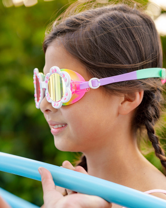 girl smiling playing poolside games wearing dandi flower shaped swim goggles in sunlit sherry showing petal detail with rhinestone and bright rainbow colored strap and gasket 