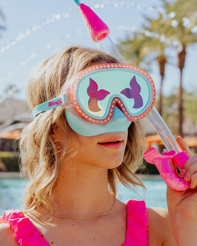 girl at swimming pool wearing blue sea kids' swim mask with nose piece in blue sushi colorway showing reflective translucent mermaid tail print lens on rhinestone glitter frame