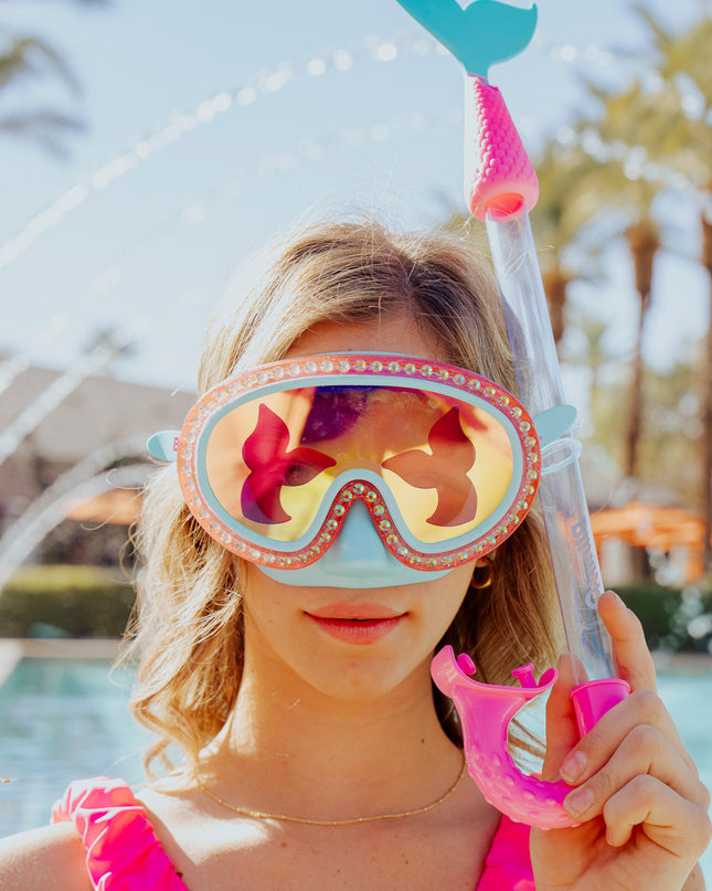 girl at swimming pool wearing blue sea kids' swim mask with nose piece in blue sushi colorway showing reflective translucent mermaid tail print lens on rhinestone glitter frame