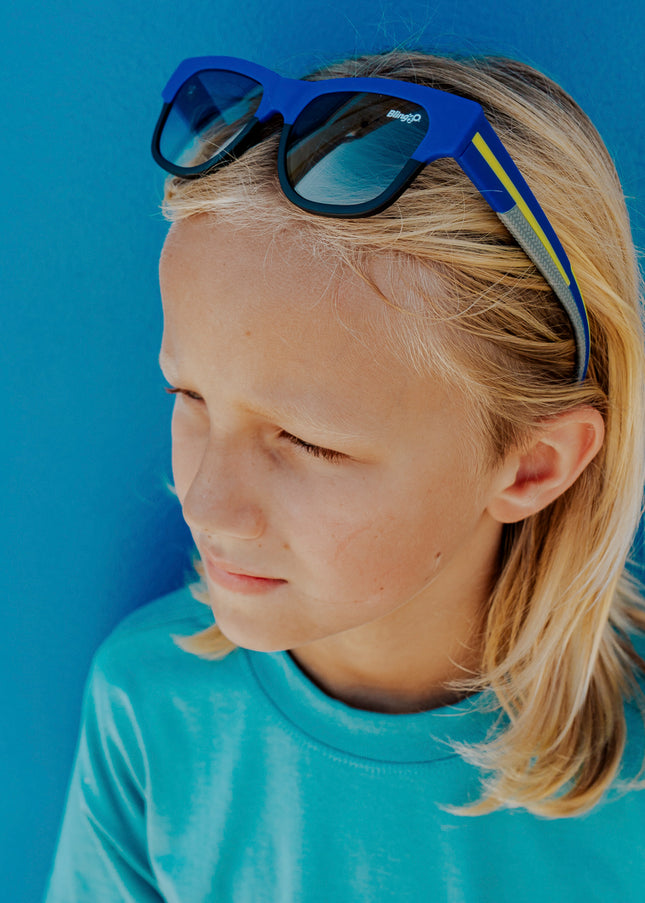 boy wearing firesland kids' sunglasses in royal sunrays on head pushing hair back 