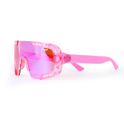 angled product shot of pink sand kids' sunglasses in color sprinkle pink featuring shield frame with 3-d sprinkles in the frame, heart insignia and all pink frame and lens