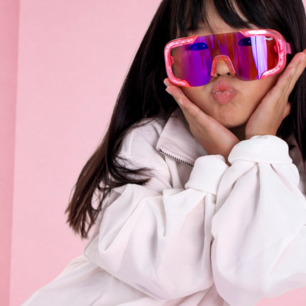 girl posing in pink studio wearing pink sand kids sunglasses in the color sprinkle pink 