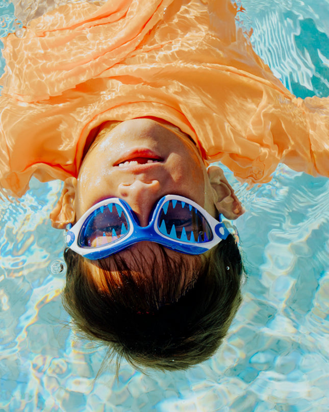 lifestyle image of child floating in pool wearing covert chomp in frost fin showing screen printed lens