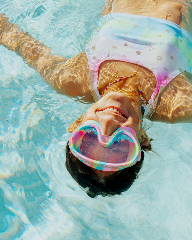 lifestyle of girl floating in pool wearing crystal current in sapphire swirl showing turquoise glitter settled at the bottom of the frame