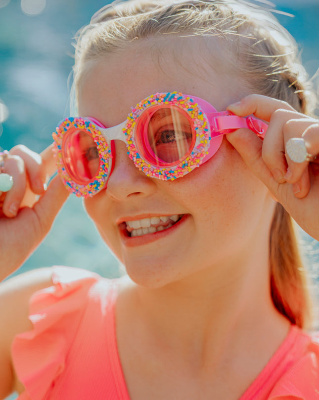 Lifestyle of girl wearing donuts 4 u swim goggles in boston creme pink showing sprinkles and pink silicone