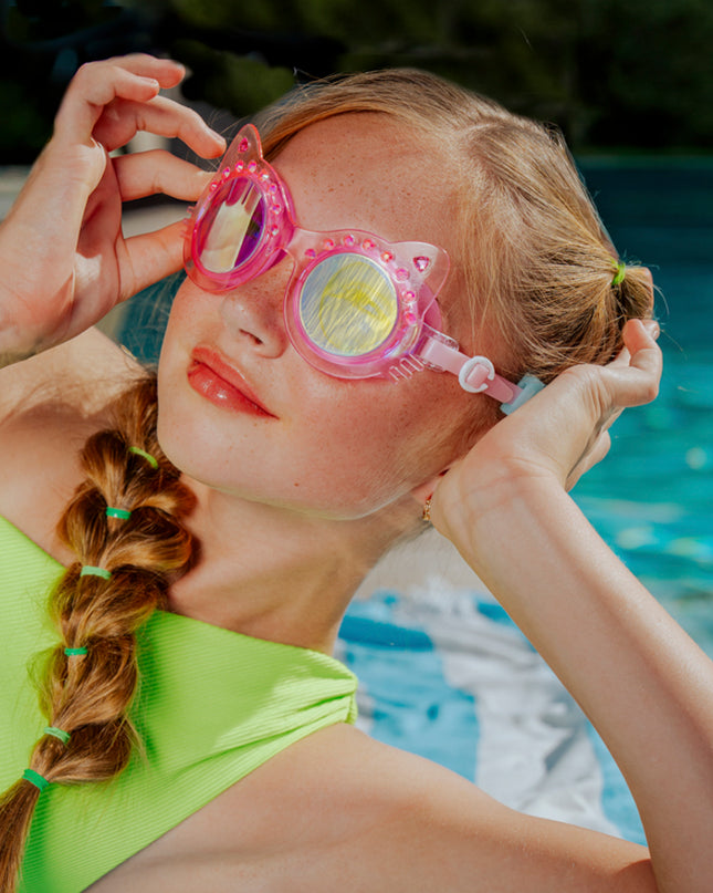 lifestyle image of girl poolside wearing frosted feline swim goggles in pink purr showing pink frame and rhinestones