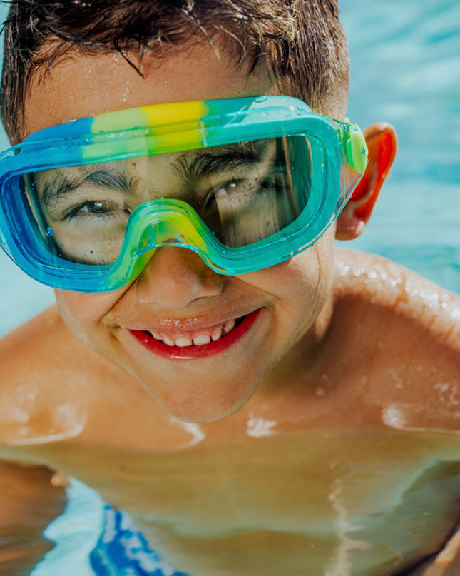 lifestyle of boy in pool swimming wearin hologram swim goggles in cyber green showing frameless lens and swirls of green silicone gasket