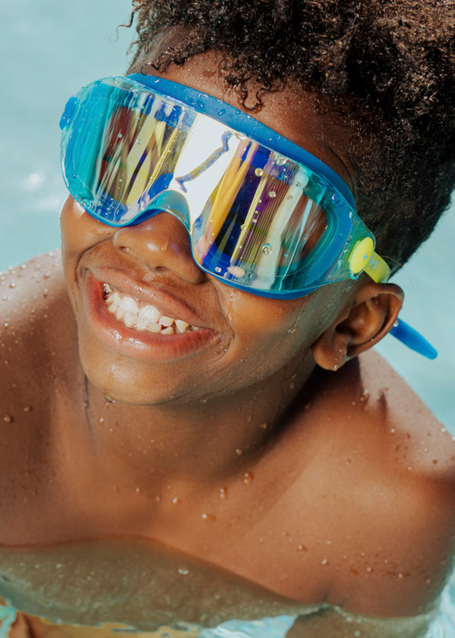 lifestyle of boy swimming wearing hologram kids swim goggles in polar stream showing frameless lens and blue gasket