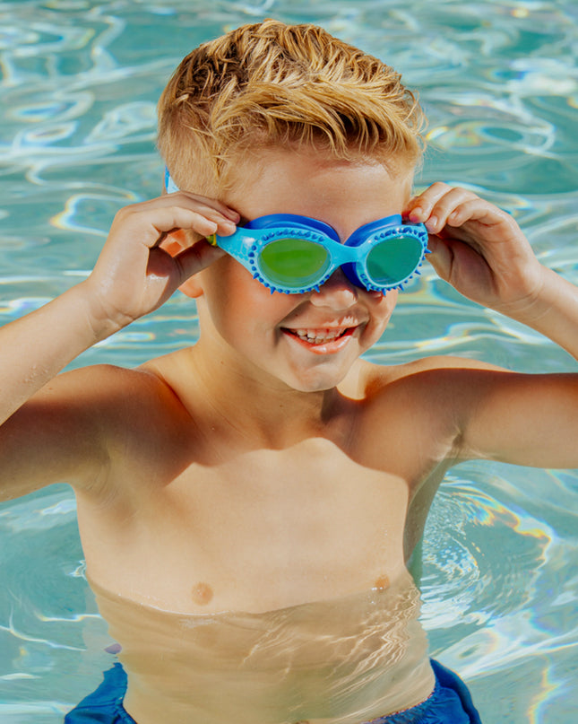 lifestyle of boy in pool smiling and posing wearing jurassic dive in raptor reef blue showing silicone spike detail
