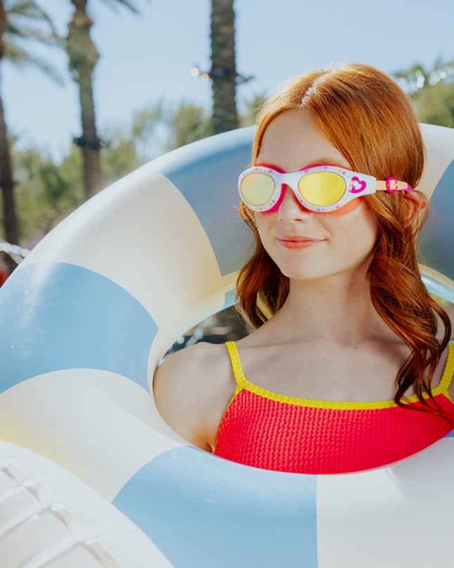 lifestyle of teen girl wearing love sparkles swim goggles in mango muse pink and orange silicone white frame swim goggles showing rhinestones and hot pink heart printed on frame