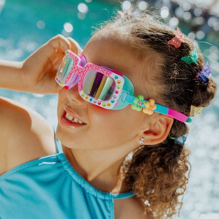 angled Lifestyle of 4 year old girl smiling wearing Pretty Girl Poppy in Petal Pop Pink kids' swim goggles showing silicone flower sliders