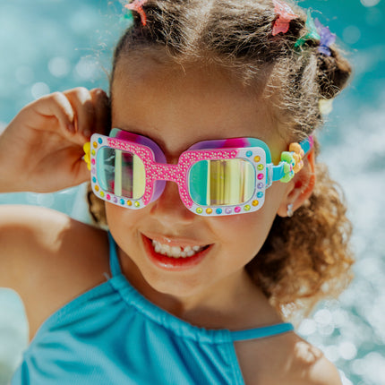Lifestyle of 4 year old girl smiling wearing Pretty Girl Poppy in Petal Pop Pink kids' swim goggles 