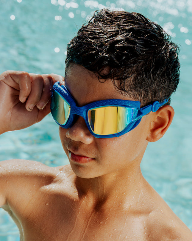 boy wearing standing in front of pool wearing streamline silicone goggles showing reflective lens and textured gasket