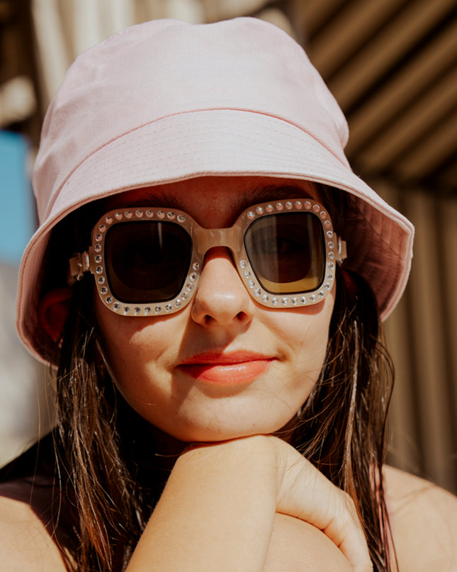 teen girl sitting poolside wearing bring vibrancy swim goggles in opal showing wide square framed swim goggles with rhinestones and tinted lens