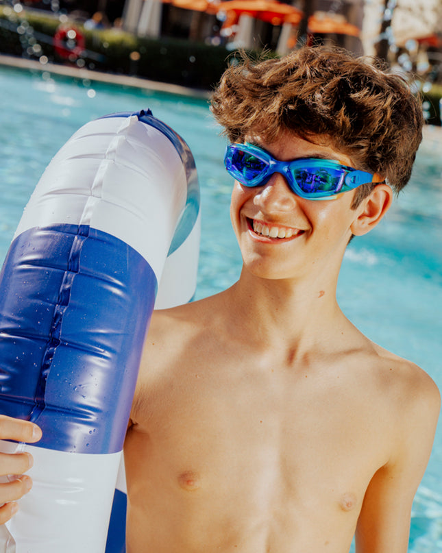 teen boy smiling standing poolside holding inner tube wearing voyage swim goggles showing reflective lens and silicone frame